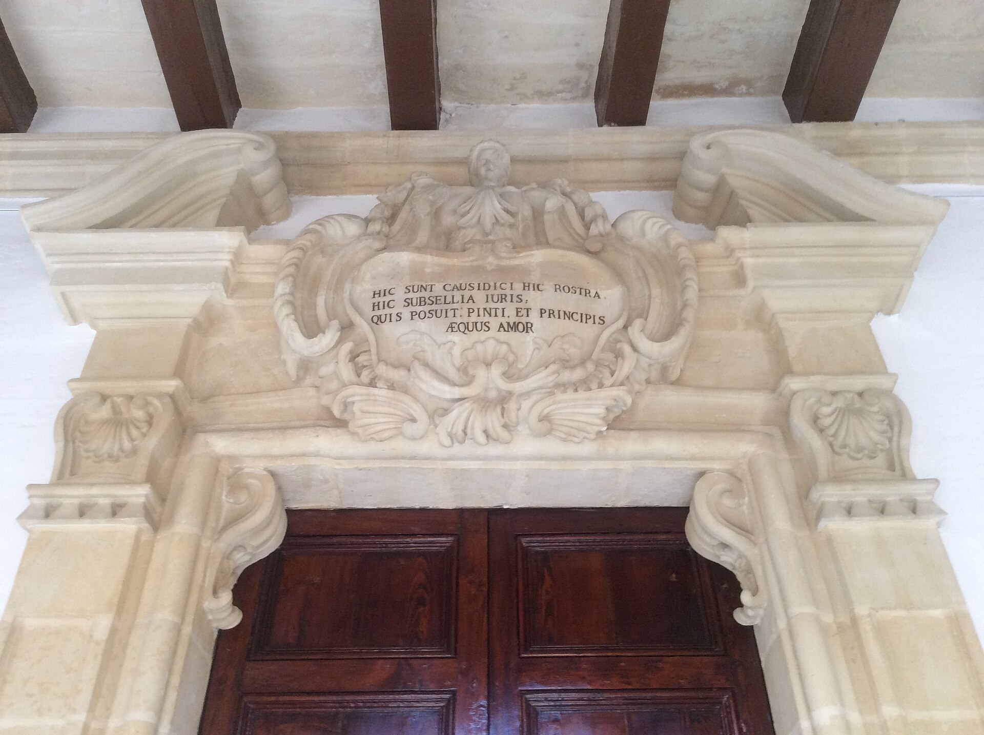Ornate baroque gilded frame and carved ceiling detail, photographed in low warm light